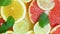 Slow motion panning video of mint leaves falling on slices of oranges, grapefruits and lemons