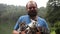 Slow motion portrait of an adult bearded man holding three kittens in the rain.