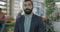 Slow motion portrait of bearded Middle Eastern man in suit standing in coworking place looking at camera