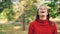 Slow motion portrait of cheerful girl in warm sweater standing in the park with glad smile, laughing and looking at