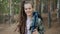 Slow motion portrait of cute young woman with dreadlocks standing in woods with backpack