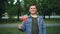 Slow motion portrait of handsome man in casual clothes waving Portuguese flag with happy smile and looking at camera