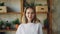 Slow motion portrait of happy young lady looking at camera and smiling then laughing standing in nice modern apartment