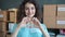 Slow motion portrait of happy young woman volunteer making heart hand gesture and smiling in charity company office