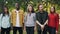 Slow motion portrait of multi-ethnic group of friends happy young people standing in the park together smiling and