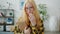 Slow motion portrait of serious teenager standing at home holding book touching glasses