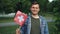 Slow motion portrait of Swiss sports fan smiling, waving flag of Switzerland and looking at camera with green trees and