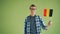 Slow motion portrait of young man waving flag of Germany and smiling