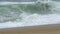 Slow motion powerful foamy white waves breaking on sandy beach.