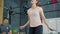 Slow motion of pretty lady doing sports in gym jumping with skipping rope training with male coach