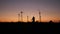 Slow-motion scene of pretty girls silhouette runs trough the hills near windmill