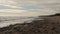 Slow motion of sea waves washing northern sandy beach with water and foam. Camera moves along stormy ocean coastline in