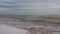 Slow motion of sea waves washing northern sandy beach with water and foam. Camera moves along stormy ocean coastline in