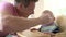 Slow Motion Shot Of Father Feeding Baby Boy In High Chair