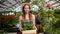 Slow motion of smiling florist woman carrying box of flowers in greenhouse
