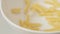 SLOW MOTION: Spiral macaroni fall on white dish close up