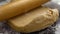 Slow motion of spreading flour on dough and rolling it with rolling pin closeup