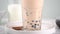 Slow motion - stirring tapioca pearl bubble milk tea in drinking glass, tasty Taiwanese popular drink on bright marble table. Home