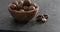 Slow motion tilt of macadamia nuts in olive wood bowl on terrazzo countertop