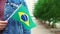Slow motion: Unrecognizable woman holding Brazilian flag. Girl walking down street with national flag of Brazil