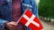 Slow motion: Unrecognizable woman holding Danish flag. Girl walking down street with national flag of Denmark