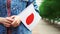 Slow motion: Unrecognizable woman holding japanese flag. Girl walking down street with national flag of Japan