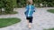 Slow motion video of cute barefoot little boy running on footpath and grass at park