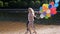 Slow motion video of happy couple running with big bunch of colorful balloons by the lake