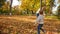 Slow motion video of little smiling boy playing in autumn park and running after his mother