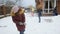 Slow motion video of two sisters having snow ball fight at backyard