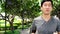 Slow motion video of young Asian man jogging while listening to music at park