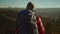 slow motion view from behind adventurous female hiker backpacker in red jacket with backpack stands on mountain top at
