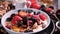 Slow motion view: pouring honey over a bowl of cereals with berries for breakfast with dry fruits