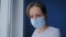 Slow motion: woman with face mask suffering from coughing, looking out of window