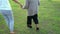 Slow-motion of woman hold hands of elderly woman and walking in park