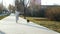 Slow motion A woman walks along an alley in a park with a funny dog on a cool spring morning, relaxing on a walk with a