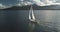 Slow motion yacht sails at mountain island shore aerial. White sailboat at Arran, Scotland, Europe