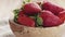 Slow motion of young female hand putting bowl of strawberries with paper card on table