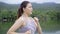 Slow motion of a young fit Asian woman running during her morning exercise at a local park with lake and mountain view, healthy li