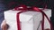 Slow motion of young girl show white gift box with red ribbon