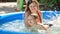 Slow motion of young smiling mother holding and supporting her little swimming in pool on sunny summer day. Family with