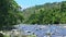 Slow panorama right at wide mountain river stream with big stone rapids