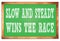 SLOW AND STEADY WINS THE RACE words on green wooden frame school blackboard