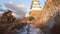 Slow tilt up from snow covered path to Japanese castle in morning golden light