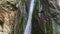 Slowly panorama down at strong mountain waterfall surrounded by high cliffs