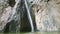 Slowly panorama up from young man swimming in transparent water to white waterfall