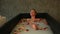 Slowly zoom in on blond woman taking bath with milk, rose petals and citrus slices