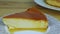 Slowly zoom in at slice of soft milk flan with caramel syrup on small round plate
