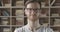 Slowmo close-up of smiling Caucasian man in eyeglasses raising eyebrow. Portrait of young bearded brunette guy standing