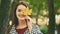 Slowmo. Happy smiling caucasian girl is imitating yellow leaf to be her eye, isolated, on blurred park background. Close